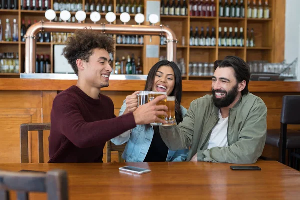 Vrienden roosteren glas bier in staaf — Stockfoto