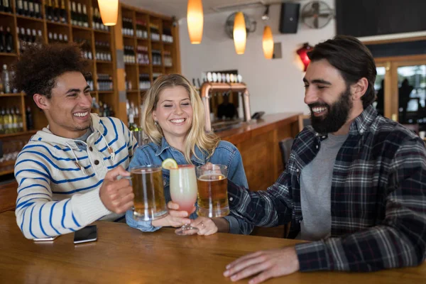 Vrienden roosteren glas van drankjes in bar — Stockfoto