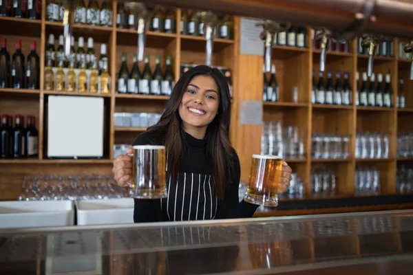Waitress holding glass of beer at counter — Stock Photo, Image