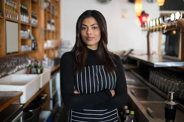 waitress standing with arms crossed in bar