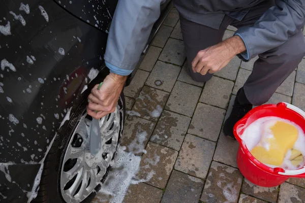 Autoservice-Mitarbeiter waschen Reifen mit Bürste — Stockfoto