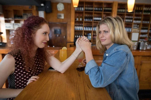 Female friends arm wrestling in bar — Stock Photo, Image