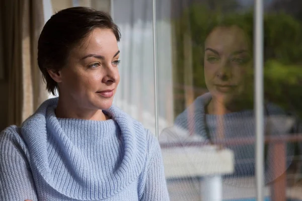 Thoughtful woman looking through window — Stock Photo, Image