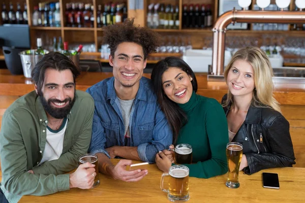 Amigos usando telefone enquanto toma um copo de cerveja — Fotografia de Stock