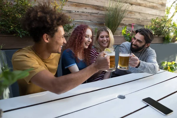 Vrienden roosteren glas van drankjes in bar — Stockfoto