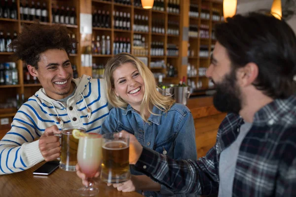 Freunde stoßen in Bar mit Getränken an — Stockfoto