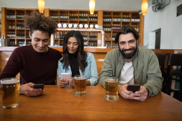 Vrienden met behulp van mobiele telefoon op tafel — Stockfoto