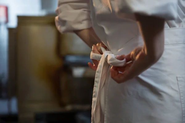 Femeie bucătar legarea uniforma ei — Fotografie, imagine de stoc