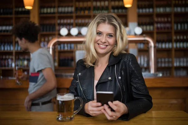 Donna che usa il telefono mentre ha un bicchiere di birra — Foto Stock