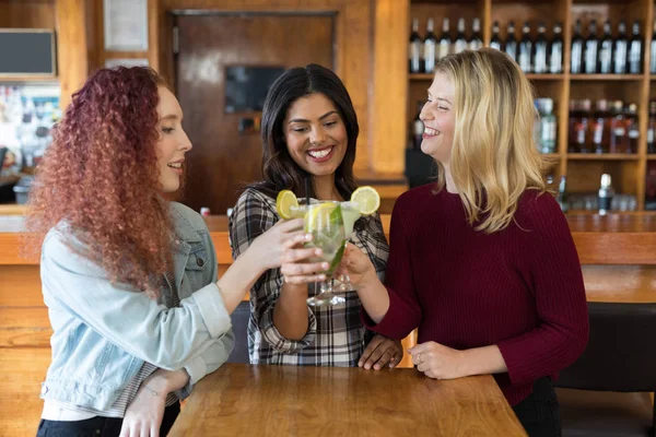 Freunde stoßen in Bar mit Getränken an — Stockfoto