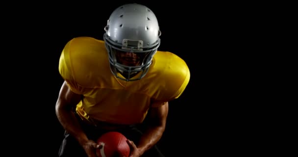 Jogador de futebol americano inclinado para a frente segurando uma bola — Vídeo de Stock