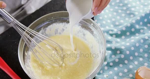 Mujer añadiendo leche a los huevos batidos en un tazón — Vídeos de Stock