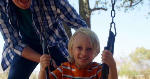 Vater schubst Sohn auf Spielplatz in Schaukel — Stockvideo