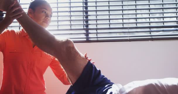 Physiotherapeut unterstützt Mann bei Beingymnastik — Stockvideo