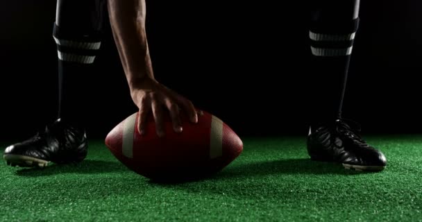 Ohýbání, drží míč hráč amerického fotbalu — Stock video