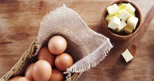 Коричневые яйца и кубики масла на деревянном столе — стоковое видео