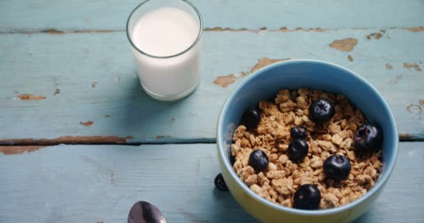 Muesli and blueberries in bowl with glass of milk — Stock Video