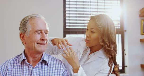 Fisioterapeuta auxiliando o homem idoso enquanto consulta — Vídeo de Stock