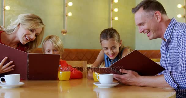 Familie kijken naar het menu in restaurant — Stockvideo