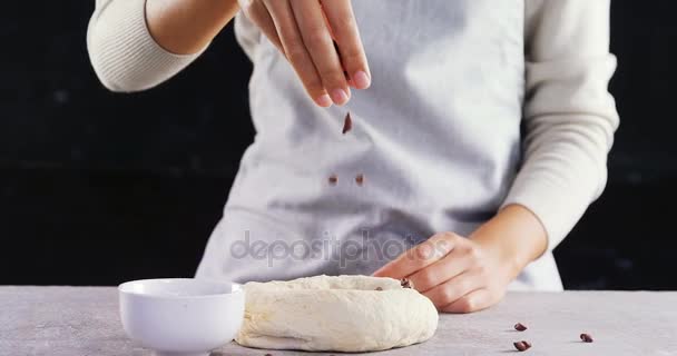 Woman adding chocolate chips into the dough — Stock Video