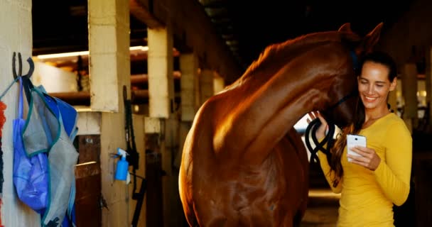 Bir at tutarken cep telefonu kullanan kadın — Stok video