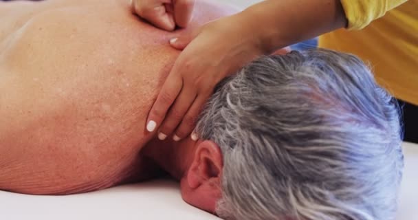 Физиотерапевт делает массаж плеч пожилому человеку — стоковое видео