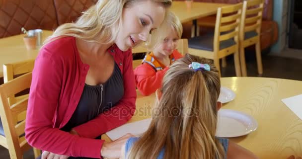 Mutter und Kinder schauen sich Speisekarte im Restaurant an — Stockvideo