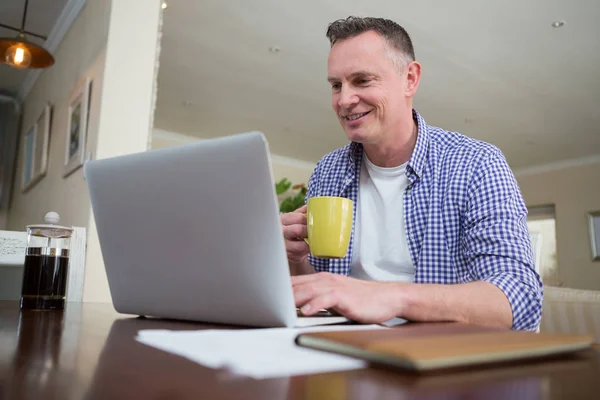 Людина використовує ноутбук, маючи каву — стокове фото
