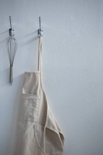 Apron and whisker hanging on hook — Stock Photo, Image