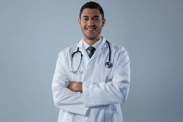 Médico sonriente de pie con las manos cruzadas —  Fotos de Stock