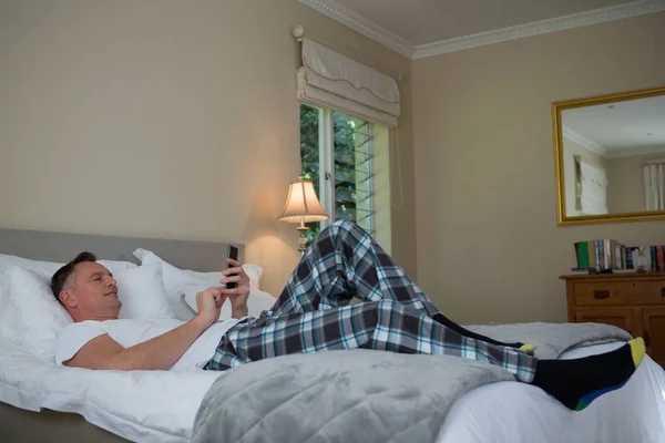 ベッドの上の携帯電話を使用している人 — ストック写真