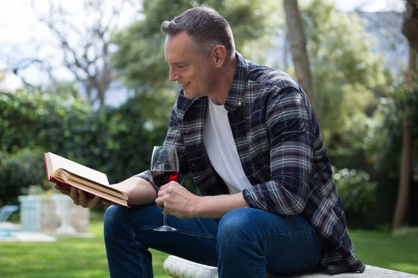 Muž čtení románu mít sklenku vína — Stock fotografie