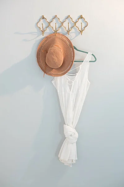 Шляпа и платье висят на белой стене — стоковое фото