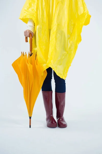 Mulher de capa amarela segurando um guarda-chuva — Fotografia de Stock