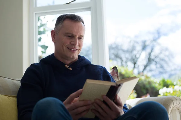 Hombre leyendo novela en sofá — Foto de Stock