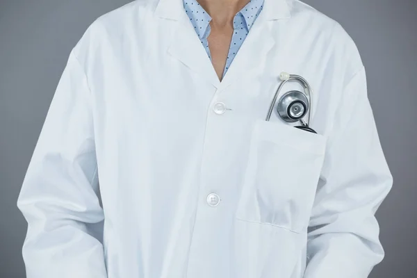 Doctor standing against grey background — Stock Photo, Image