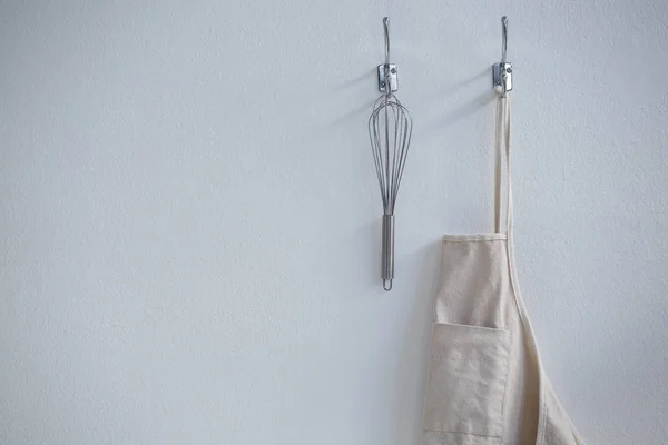Apron and whisker hanging on hook — Stock Photo, Image