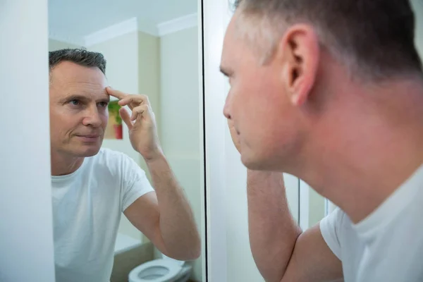 Hombre mirando su cara en el espejo — Foto de Stock