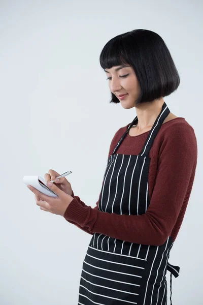 Una camarera sonriente escribiendo una orden en el bloc de notas —  Fotos de Stock