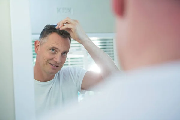 Hombre peinándose el pelo en el baño — Foto de Stock