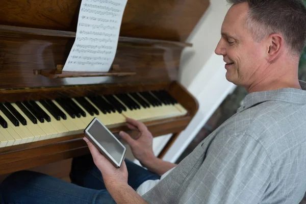 Mann benutzt digitales Tablet beim Klavierspielen — Stockfoto
