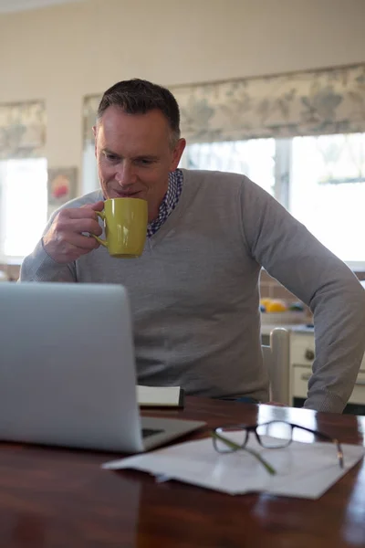 Hombre usando el ordenador portátil mientras toma café — Foto de Stock