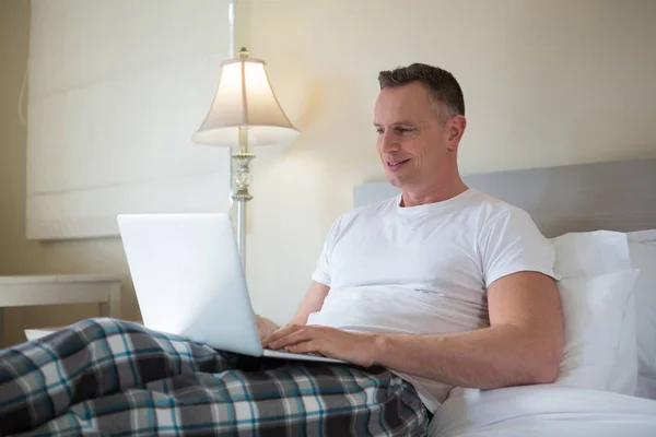 Mann benutzte Laptop auf Bett im Schlafzimmer — Stockfoto