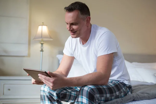Uomo utilizzando tablet sul letto in camera da letto — Foto Stock