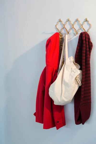 Warm clothes and bag hanging on hook — Stock Photo, Image