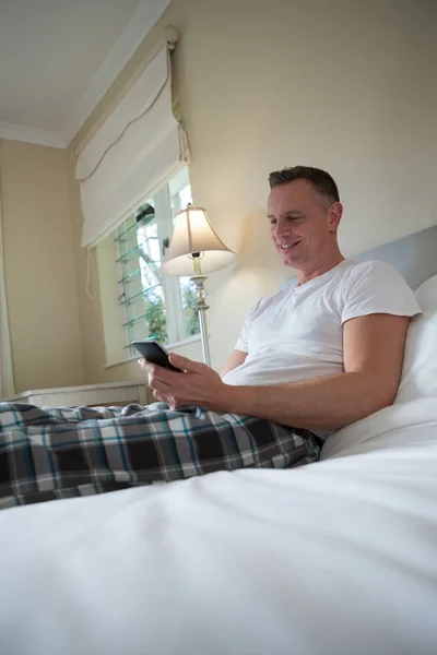 寝室でベッドの上の携帯電話を使用している人 — ストック写真