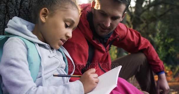 Kid and teacher taking notes — Stockvideo