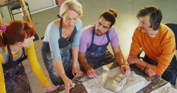 Преподаватель рисования помогает художникам в литье глины — стоковое видео