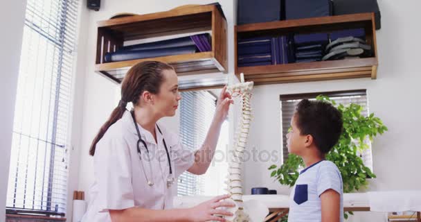 Фізіотерапевт пояснює модель хребта пацієнту — стокове відео