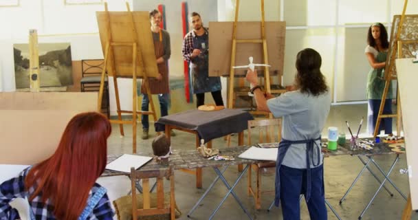 Учитель держит фигурку во время общения с художником — стоковое видео